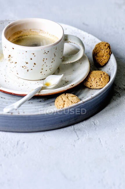 Еспресо в чашці з ложкою і маленьким печивом — стокове фото