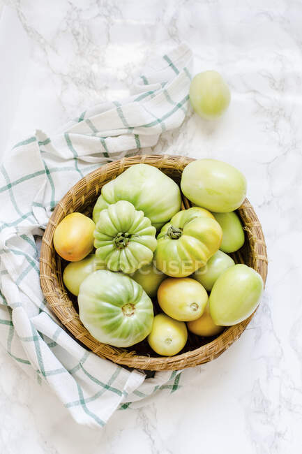 Tomates verdes en una cesta - foto de stock