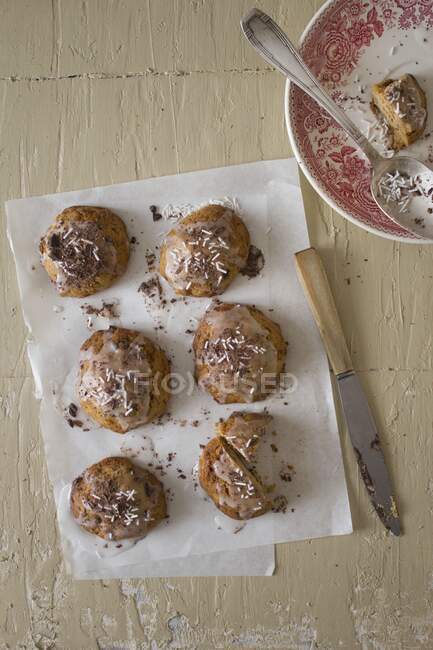 Glazed cookies with coconut shavings, plate with spoon and knife on table — Stock Photo