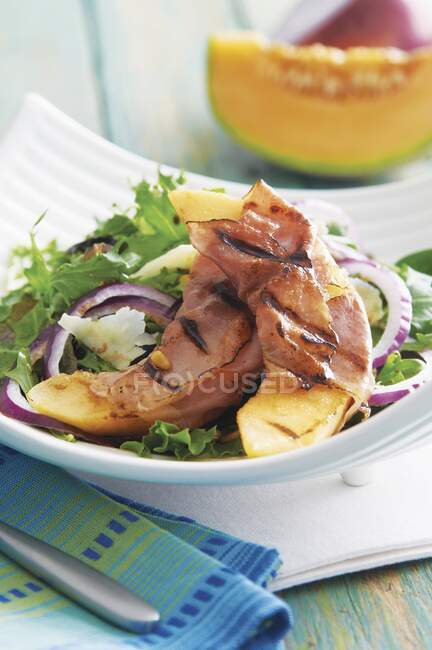 Zeppe di melone alla griglia avvolte nel prosciutto e servite sul letto di insalata di foglie — Foto stock