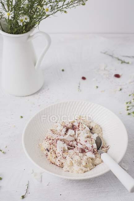 Overnight oats or bircher muesli with coconut and cranberries, and fresh daisies — Stock Photo