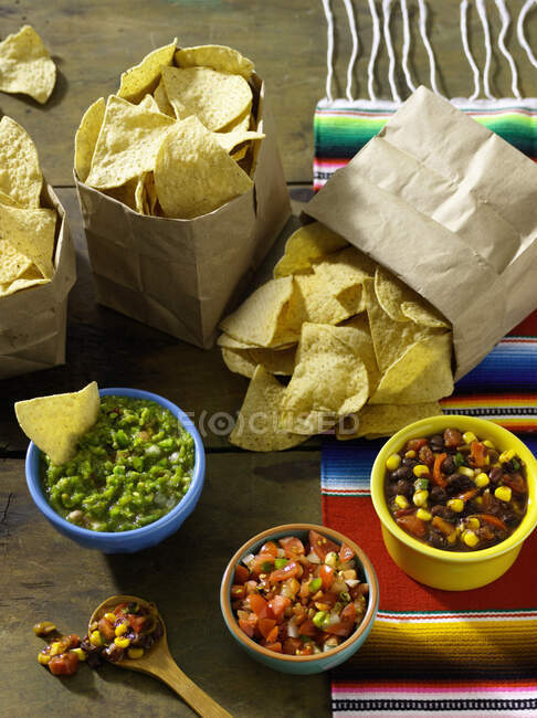 Três sacos de chips de tortilla servidos com trio de salsa — Fotografia de Stock