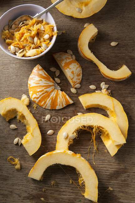 Sliced ??munchkin pumpkins and pumpkin seeds on a rustic wooden surface — Stock Photo