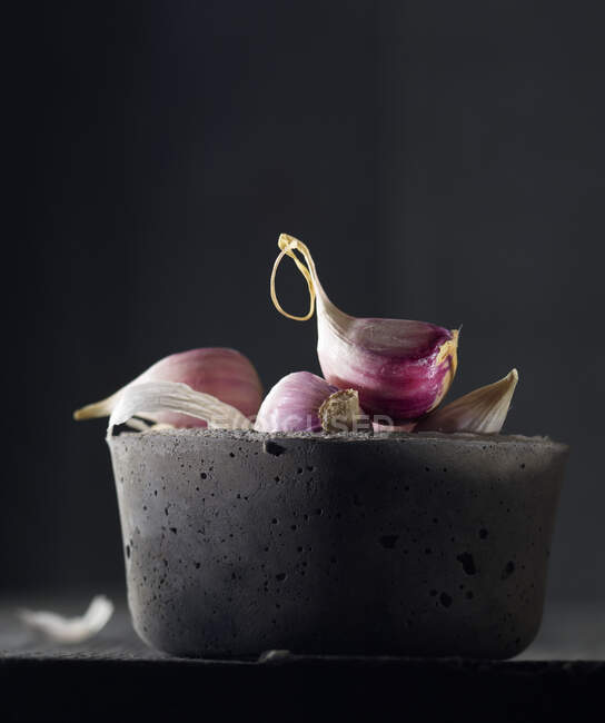 Garlic cloves in a grey concrete bowl — Stock Photo