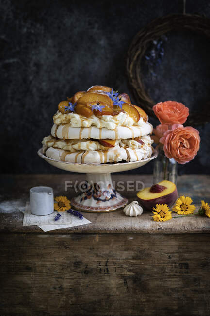 Big pavlova cake with peaches and flowers — Stock Photo