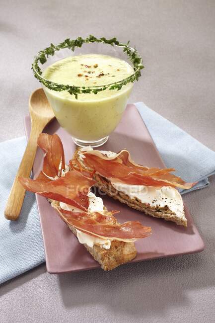 Grilled bread topped with raw ham served with cold cream of cucumber soup — Stock Photo
