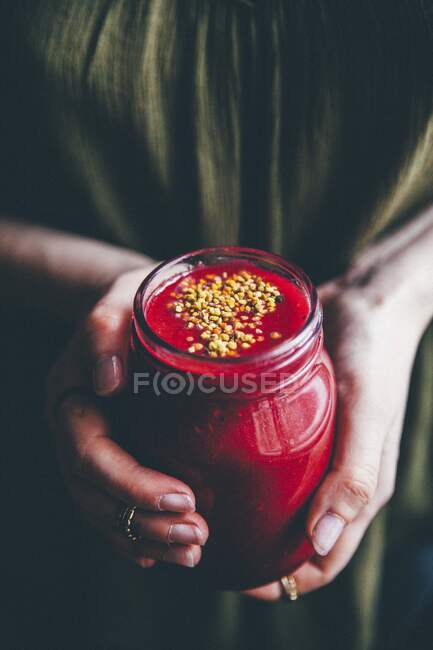 Una donna che tiene un bicchiere di frullato di lamponi — Foto stock