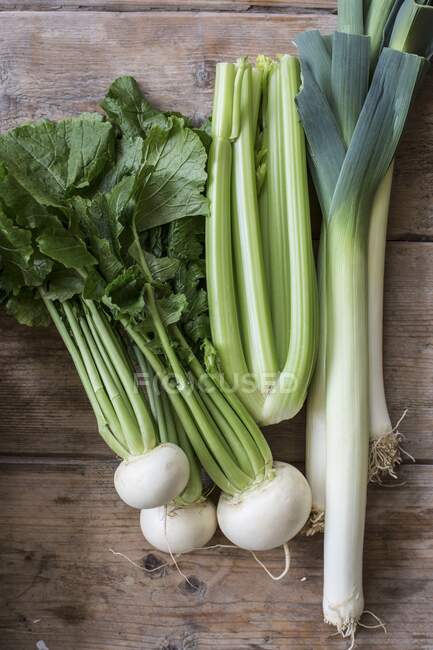 White turnip, celery and leek on a wooden background — Stock Photo