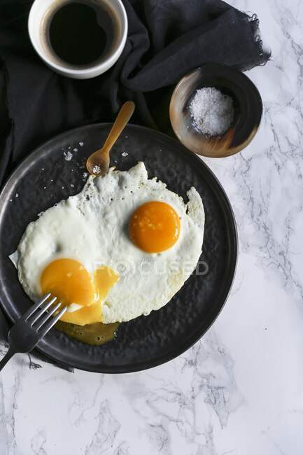 Fried eggs with salt and cup of coffee — Stock Photo