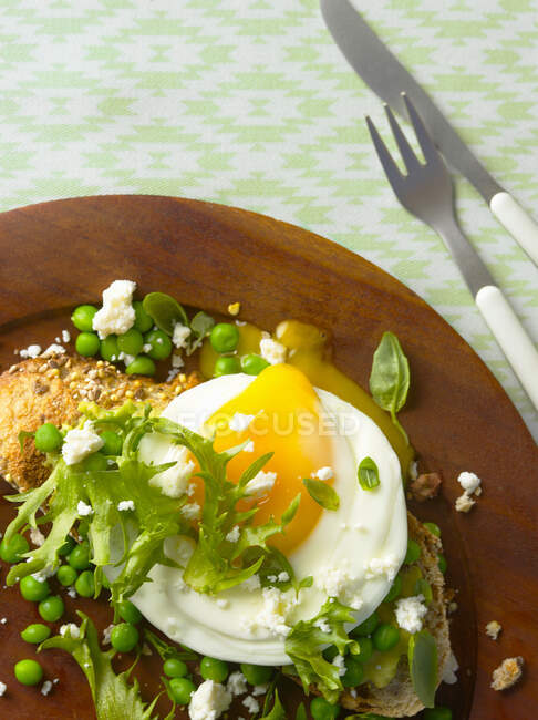 Смажене яйце на скибочці хліба з горохом, салатом і сиром фета — стокове фото