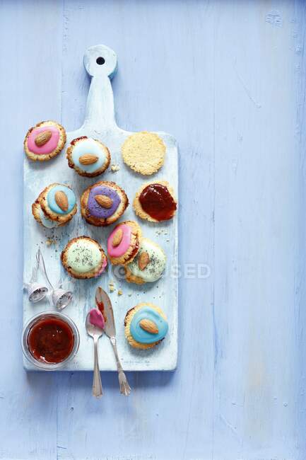 Bunt glasierte Kekse mit Mandeln auf blauem Brett — Stockfoto
