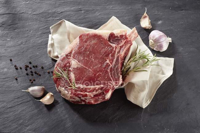 A raw beef rib, garlic, rosemary and peppercorns — Stock Photo