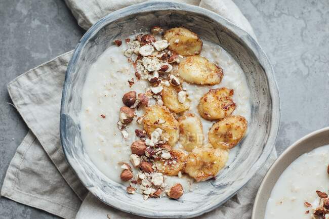 Oat porridge with caramelized bananas and hazelnuts — Stock Photo