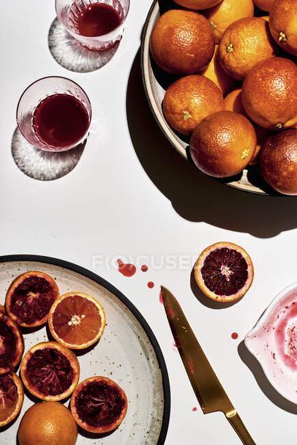 Соковыжималка на нарезанной крови апельсин и стакан сока — стоковое фото