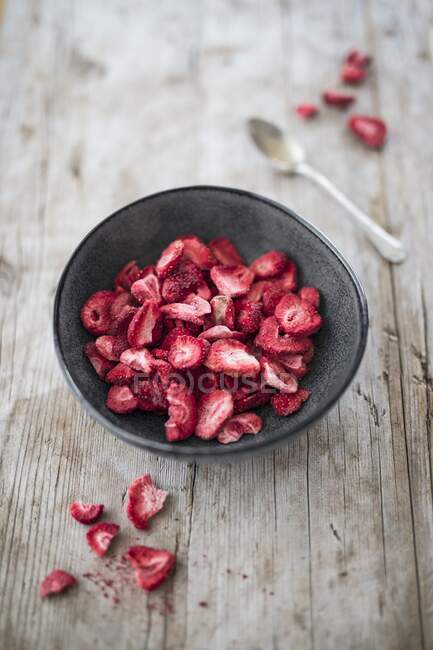 Getrocknete Erdbeeren in Schüssel und auf Holztisch mit Löffel — Stockfoto