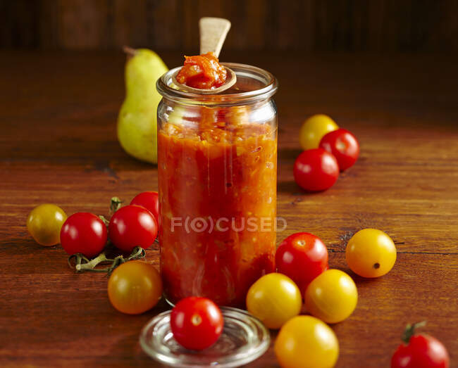 Hausgemachtes Tomatenchutney mit Birne, Ingwer, Essig, Kirschtomaten, Chili, Koriander, Nelken und Thymian — Stockfoto