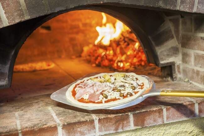 Pizza capricciosa davanti a un forno a legna — Foto stock