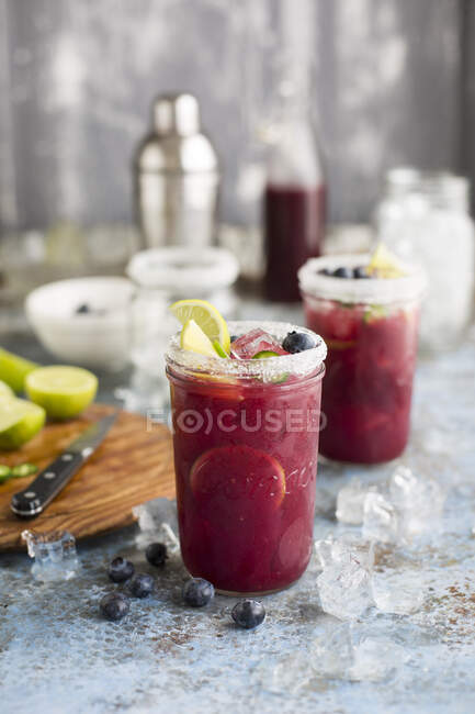 Margarita cocktails in glasses with sugar, blueberries, green chili and lime — Stock Photo