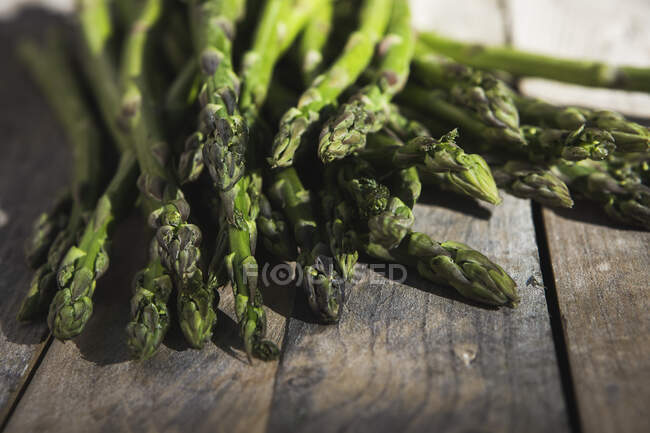 Asperges vertes fraîches sur une planche de bois — Photo de stock