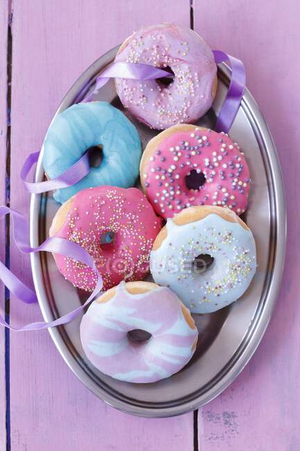 Rosquillas con glaseado de colores brillantes y salpicaduras de azúcar - foto de stock