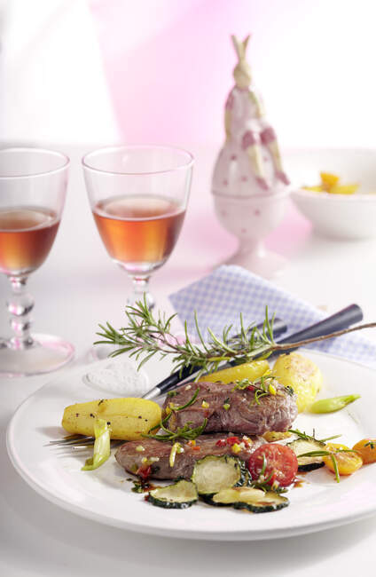 Lamb steaks in an orange and honey marinade with rosemary potatoes and a courgette and tomato medley — Stock Photo