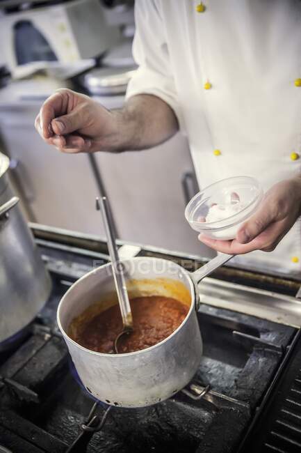 Добавление соли в томатный соус — стоковое фото