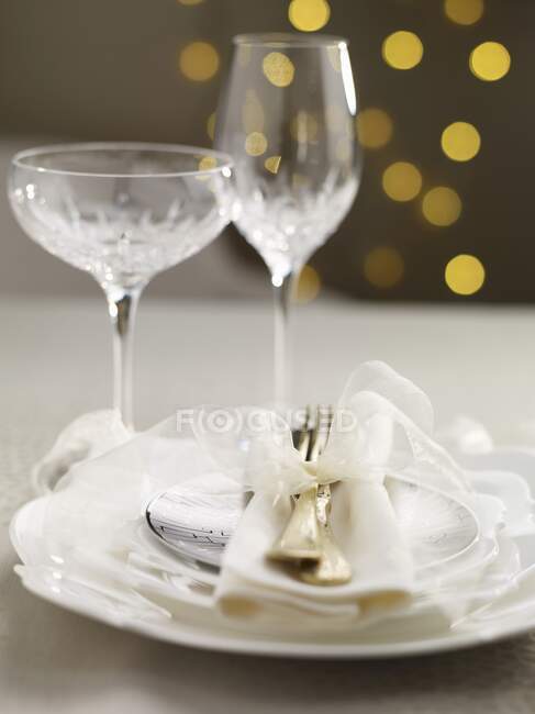 A Christmas table setting with a white bow and crystal glasses — Stock Photo