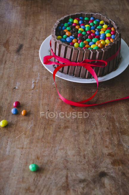 Ein Schokoladenkuchen mit Schokoriegeln auf einem Holztisch mit roter Schleife zum Muttertag — Stockfoto