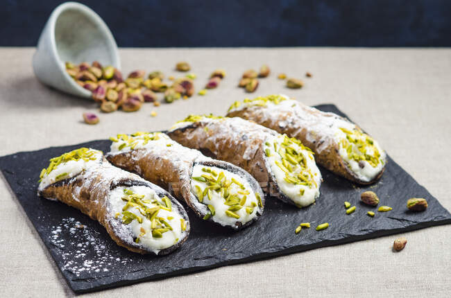 Italian sicilian cannoli with sweet ricotta cheese, chocolate chips and garnished with chopped pistachios and icing sugar — Stock Photo