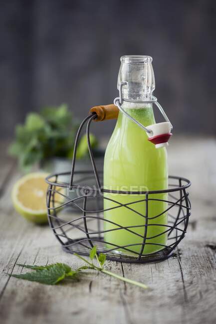 Nettles lemonade in mini bottle inside mini wire basket — Stock Photo