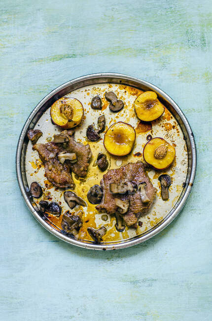 Duck breast with caramelized peaches and mushrooms on a round tray — Stock Photo