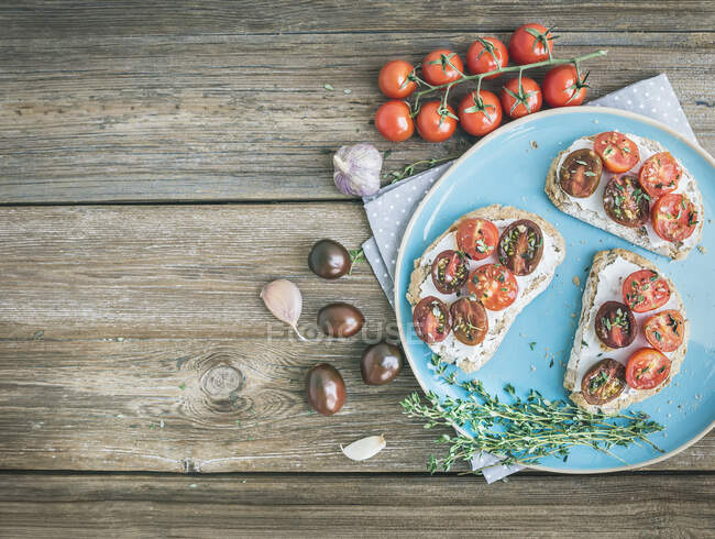 Café da manhã rústico conjunto de sanduíches com creme de queijo macio, tomate cereja assado com alho e tomilho — Fotografia de Stock