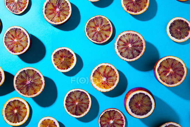 Mitades de naranja sangre sobre fondo turquesa - foto de stock