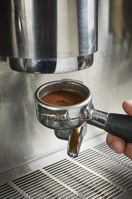 Filterhalter mit frisch gemahlenem Kaffee an der Kaffeemaschine befestigen — Stockfoto