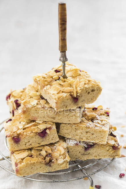 A stack of butter cake slices with pomegranate seeds and flaked almonds — Stock Photo