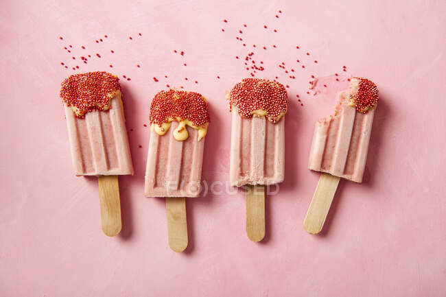 Salpicos de sorvete de morango com polvilhas de açúcar, um com uma mordida retirada — Fotografia de Stock