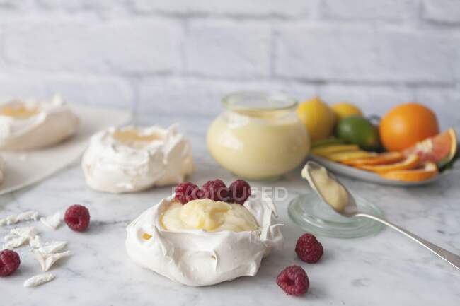 Nidos de merengue con crema de cuajada y frambuesas - foto de stock