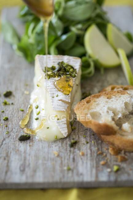 Brie mit Honig, Pistazien, Baguette, Salat und Äpfeln — Stockfoto