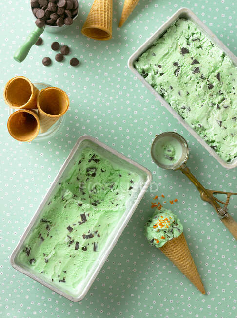 Homemade mint ice cream in metal containers and in cones — Stock Photo