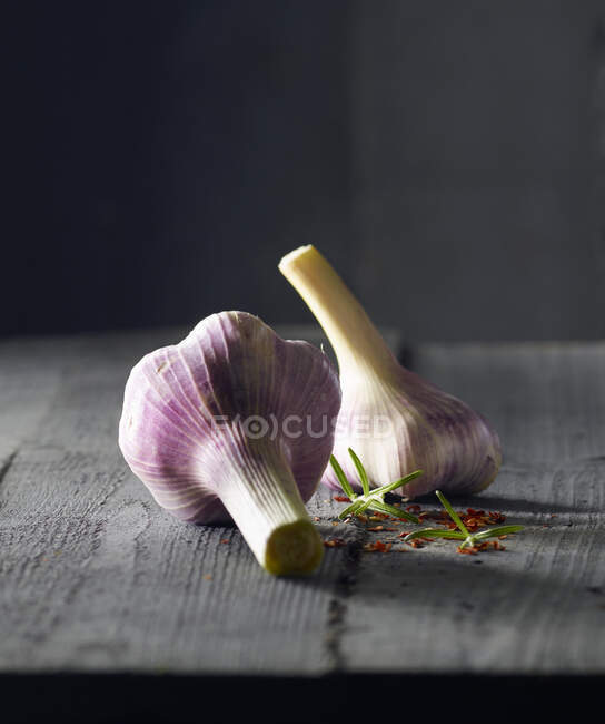 Two garlic bulbs with rosemary and chillies — Stock Photo