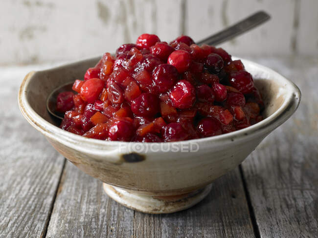 Fresh red cranberry in a wooden dish on a white plate — Stock Photo