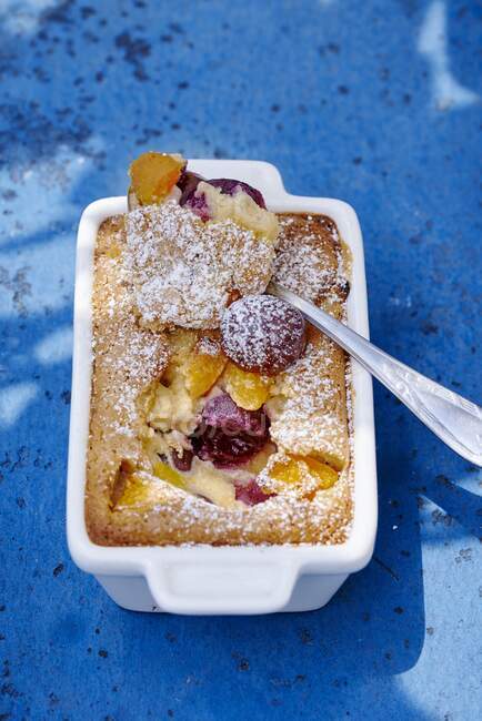 Clafoutis pie with apricots and cherries with powder sugar and spoon in tin — Stock Photo