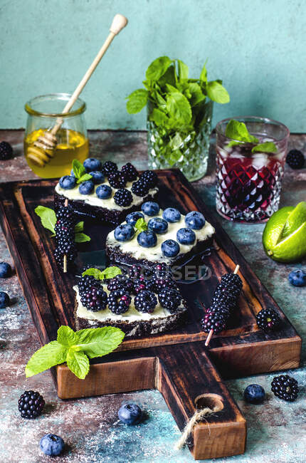 Sandwiches with berries and honey and blackberries mojito — Stock Photo