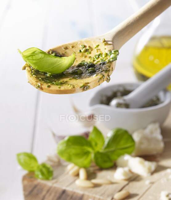 A wooden spoon with pesto and a basil leaf — Stock Photo
