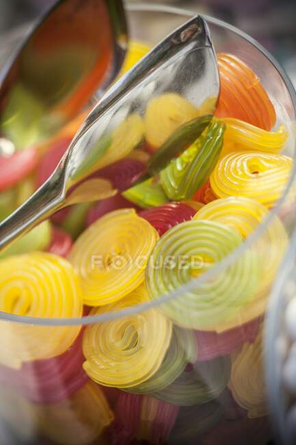 Rodas de goma de frutas em um frasco de vidro com pinças — Fotografia de Stock