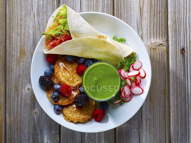 A breakfast tray with pancakes, berries, a smoothie and a wrap — Stock Photo