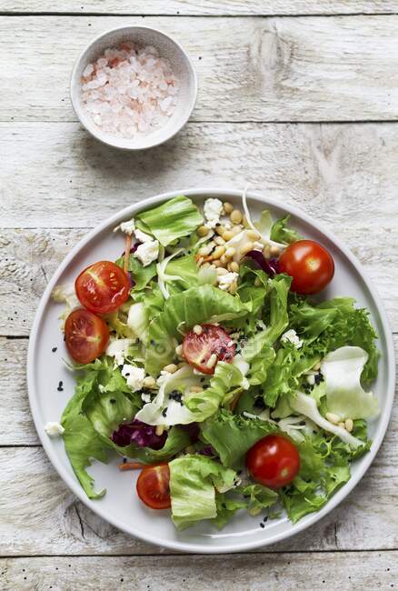 Mixed salad with tomatoes, goat cheese, pine nuts and sesame seeds — Stock Photo
