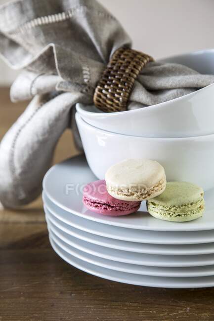 Colorful macarons on stack of plates and bowls — Stock Photo