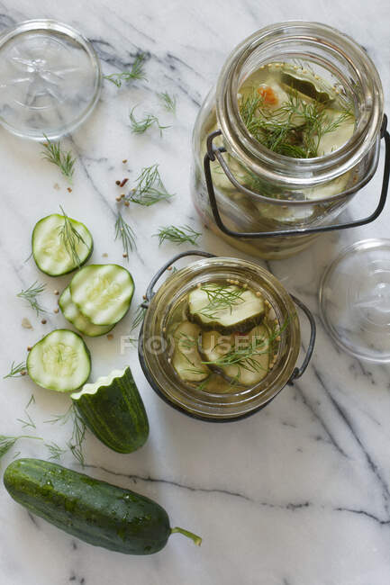 Pepinos de decapagem inteiros e fatiados marinando em frascos de vidro vintage — Fotografia de Stock