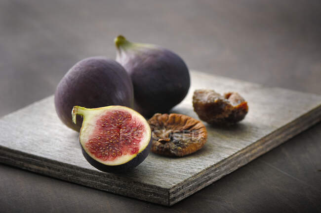 Fresh and dried figs on wooden board — Stock Photo